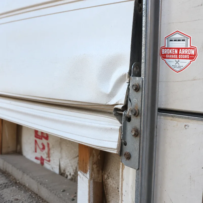 Creased steel garage door section around a hinge line causing tracking problems