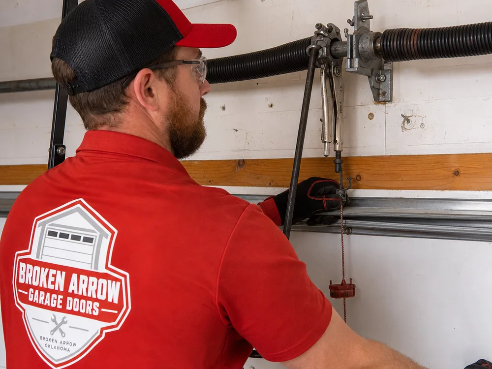 Contractor working on a torsion spring system with winding bars and locking pliers